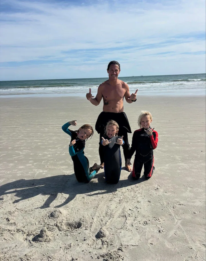 Surf camp instructor coaching a young surfer on the beach at Cocoa Beach Florida